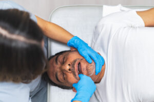 TMJ orofacial pain exam with a healthcare worker checking a patient’s mouth